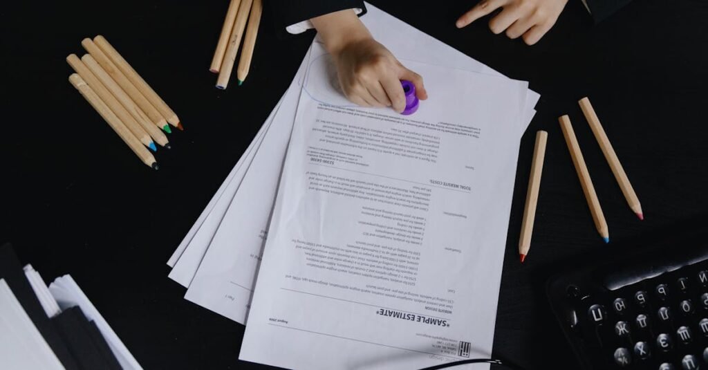 Hands working with documents and colored pencils on a black desk view.